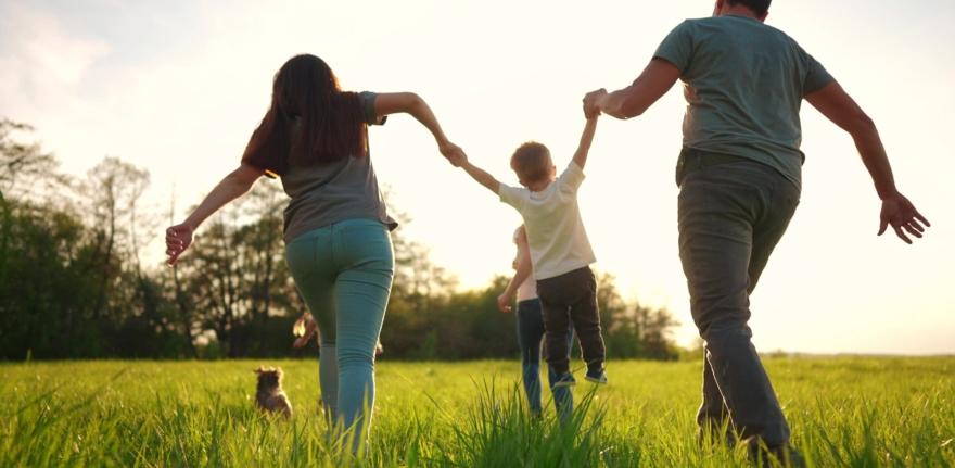 happy family running in park in summer. mom and dad hold their son by the hands run throw up in the forest park on the grass in the summer. happy family kid dream concept lifestyle